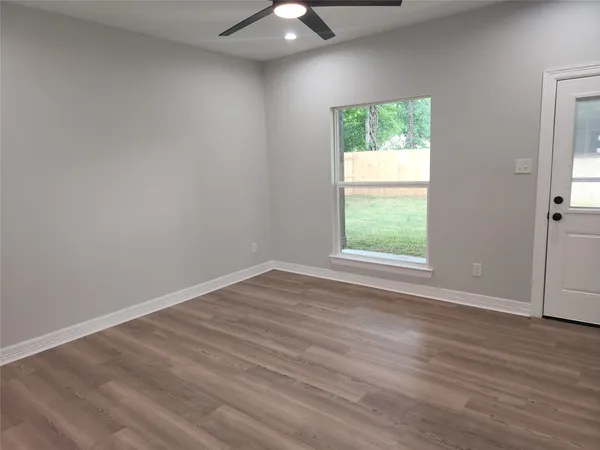 an empty room with wooden floor and windows