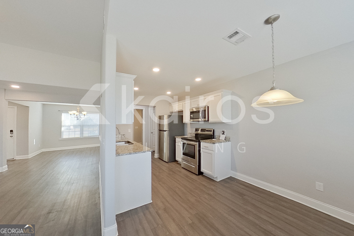 228 Western Red Cedar Drive Springfield, GA 31329 - Photo 7 of 27 a kitchen with stainless steel appliances kitchen island wooden floors stove and white cabinets