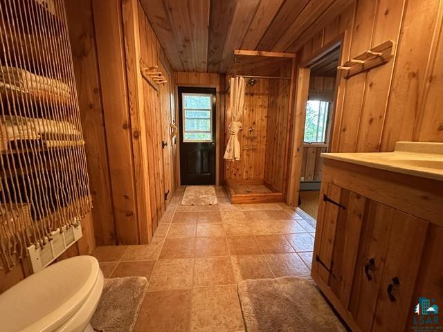 2763 Van Vac Road Ely, MN 55731 - Photo 28 of 37 Rustic full bathroom featuring plank wood walls and ceiling, a standing shower with wood-finish base, a wood-finish vanity with countertop, and neutral-toned floor tiling