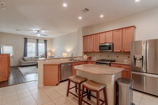 a kitchen with stainless steel appliances granite countertop a refrigerator a stove a sink a dining table and chairs