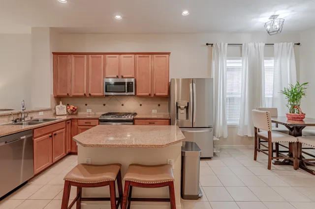 a kitchen with stainless steel appliances a stove a sink a microwave a refrigerator and chairs