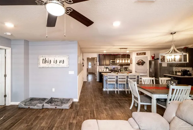 a dining room with wooden floor a chandelier fan a wooden table and chairs