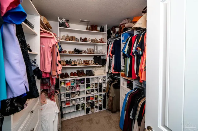 a view of walk in closet with clothes and shoes
