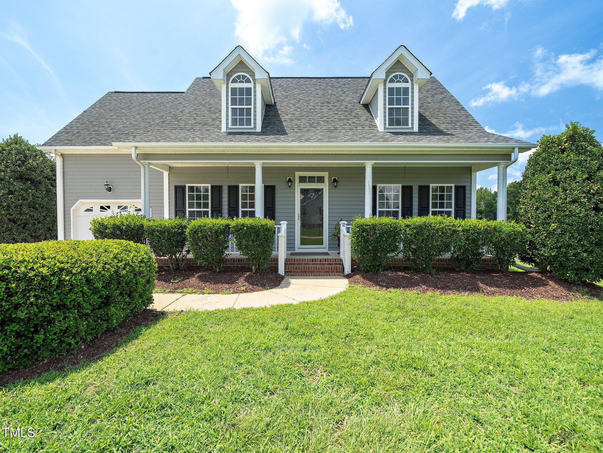 a front view of a house with a yard and plants