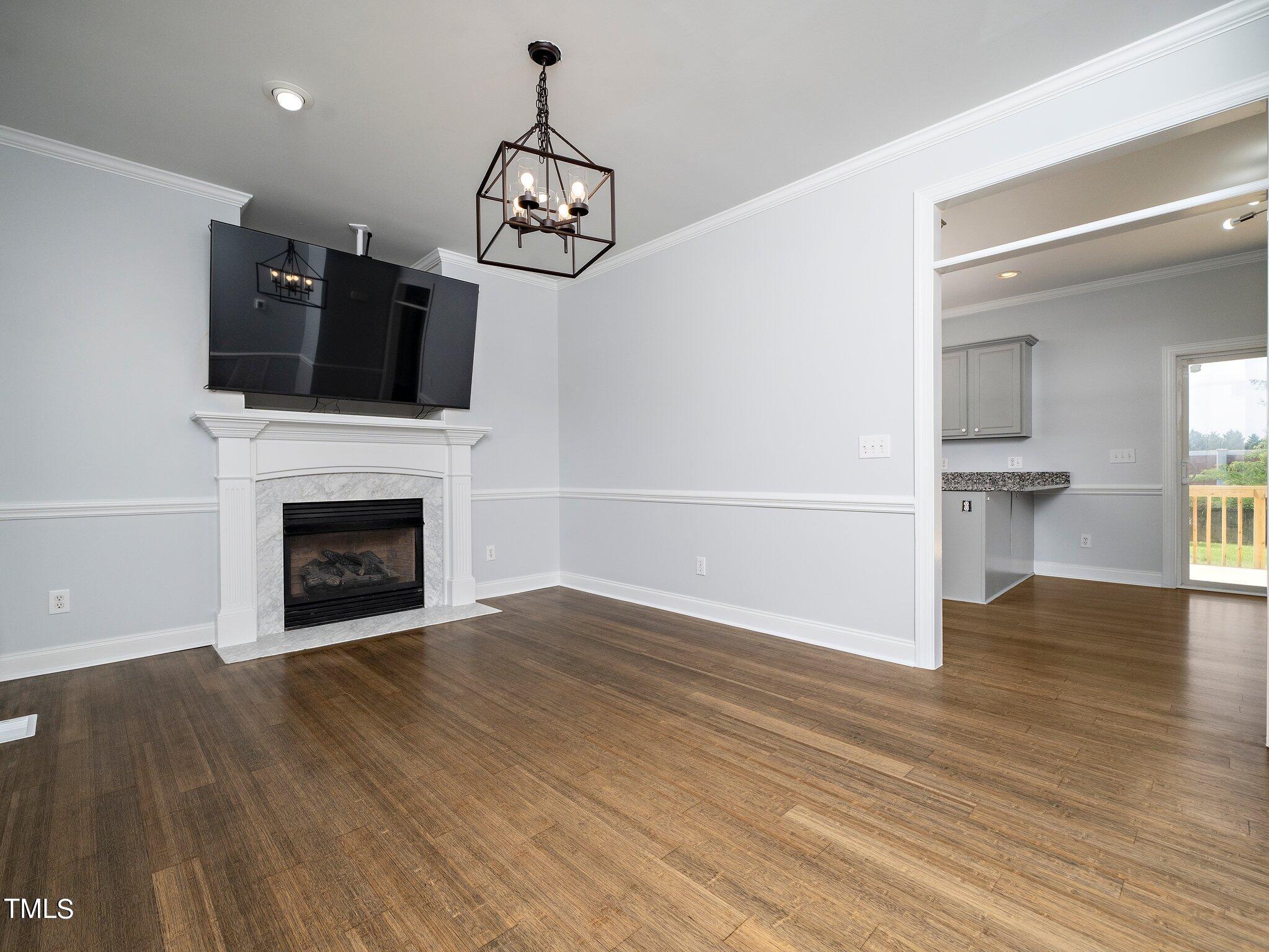5004 Contender Drive Raleigh, NC 27603 - Photo 17 of 28 a view of a livingroom with a fireplace a chandelier and wooden floor