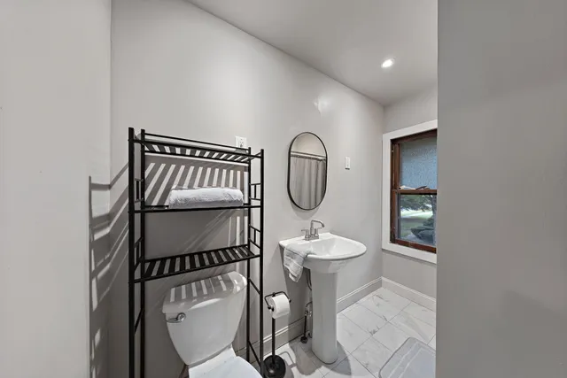 a bathroom with a toilet a sink and mirror