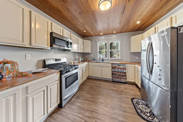 a kitchen with stainless steel appliances granite countertop a refrigerator a sink dishwasher a stove and white countertops with wooden floor