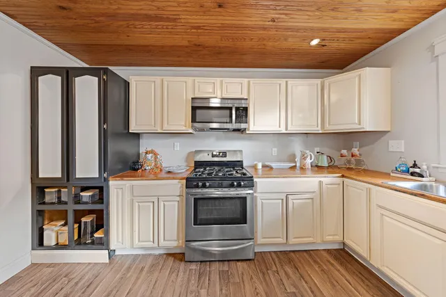 a kitchen with granite countertop a stove top oven a sink dishwasher and white cabinets with wooden floor