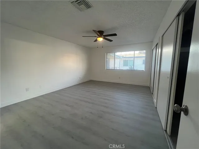 an empty room with windows and fan