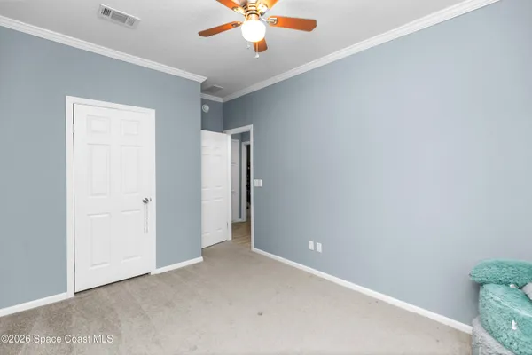 an empty room with a ceiling fan and carpet