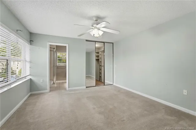 an empty room with windows and fan