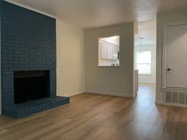 a view of a livingroom with wooden floor and a fireplace