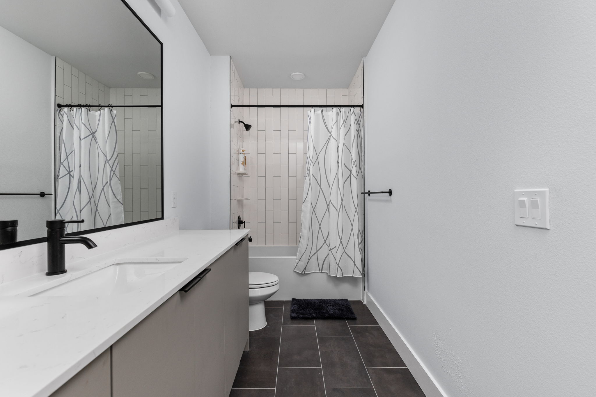 2500 Longview Street, Unit 405 Austin, TX 78705 - Photo 19 of 28 Bathroom with vanity, shower / bathtub combination with curtain, and dark tile patterned floors