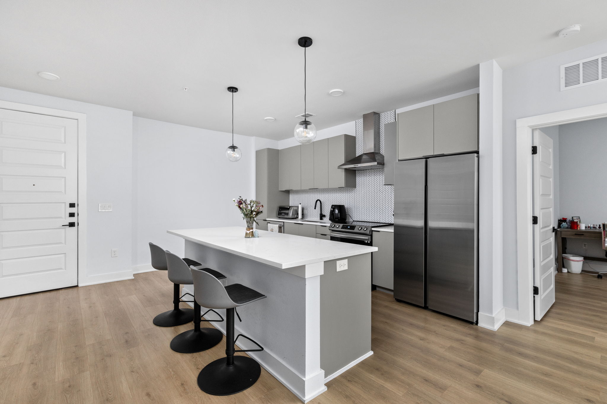 2500 Longview Street, Unit 405 Austin, TX 78705 - Photo 3 of 28 Kitchen featuring gray cabinets, stainless steel appliances, a kitchen bar, decorative backsplash, and a center island
