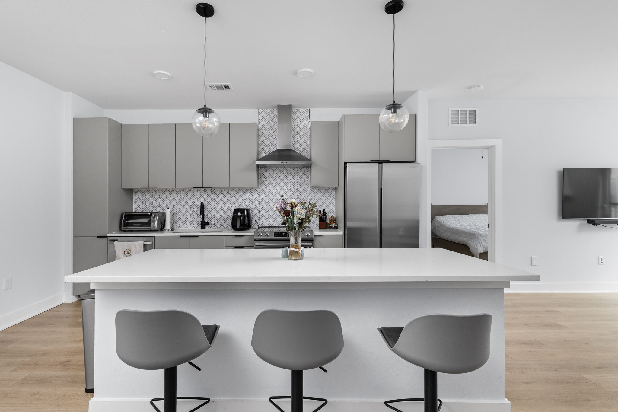 2500 Longview Street, Unit 405 Austin, TX 78705 - Photo 4 of 28 Kitchen with gray cabinetry, light wood-style floors, pendant lighting, and stainless steel appliances