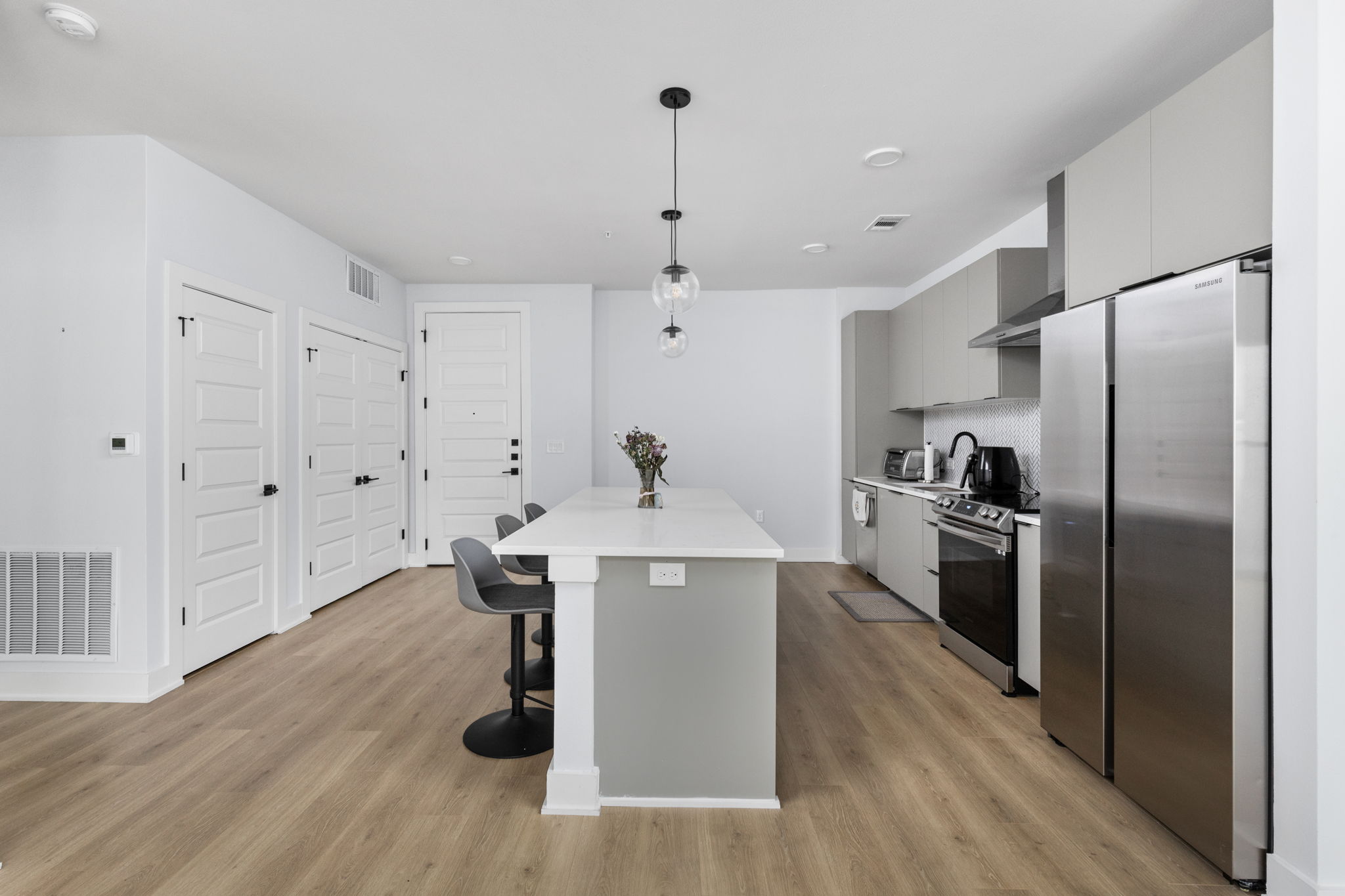 2500 Longview Street, Unit 405 Austin, TX 78705 - Photo 5 of 28 Kitchen featuring stainless steel appliances, gray cabinets, a center island with sink, a kitchen breakfast bar, and decorative light fixtures