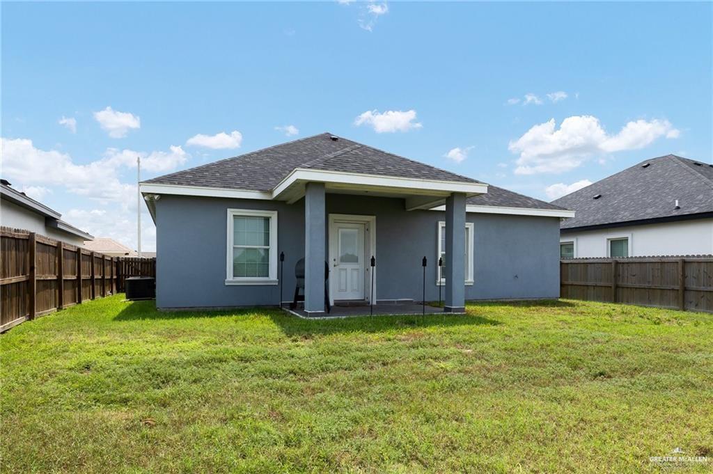 521 Oak Ridge Street Donna, TX 78537 - Photo 17 of 21 Expansive backyard featuring a manicured lawn, full privacy fencing, and a covered patio area with an exterior door