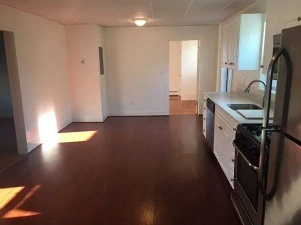 a view of a kitchen with fridge and wooden floor