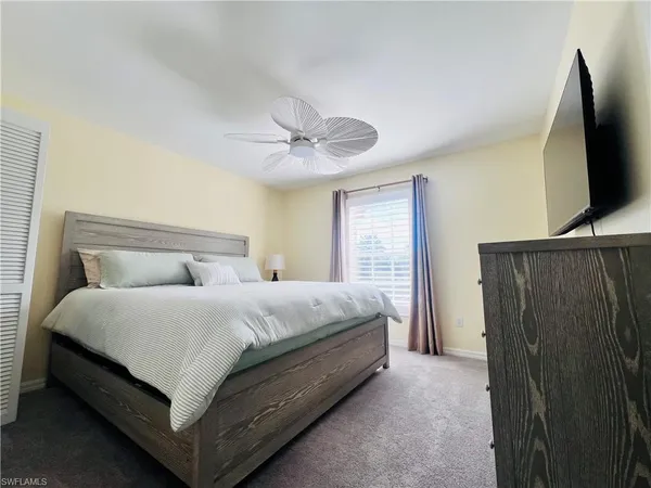 a bedroom with a bed flat screen tv and a large window