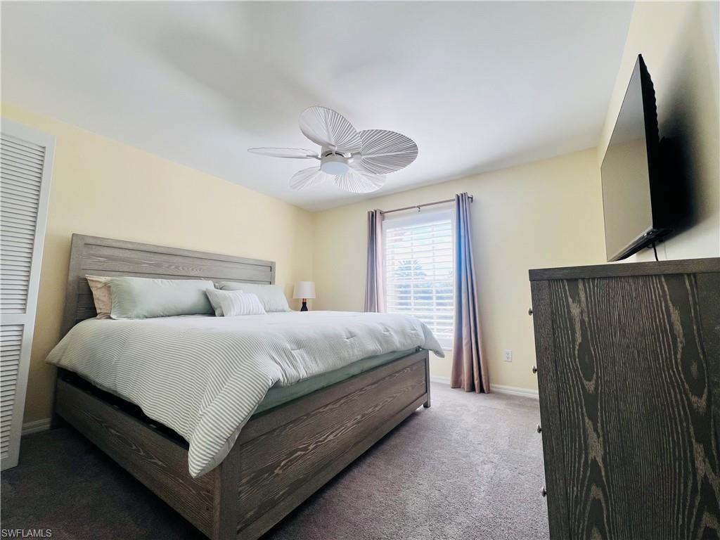 8073 Panther Trail, Unit 1404 Naples, FL 34113 - Photo 18 of 28 a bedroom with a bed flat screen tv and a large window