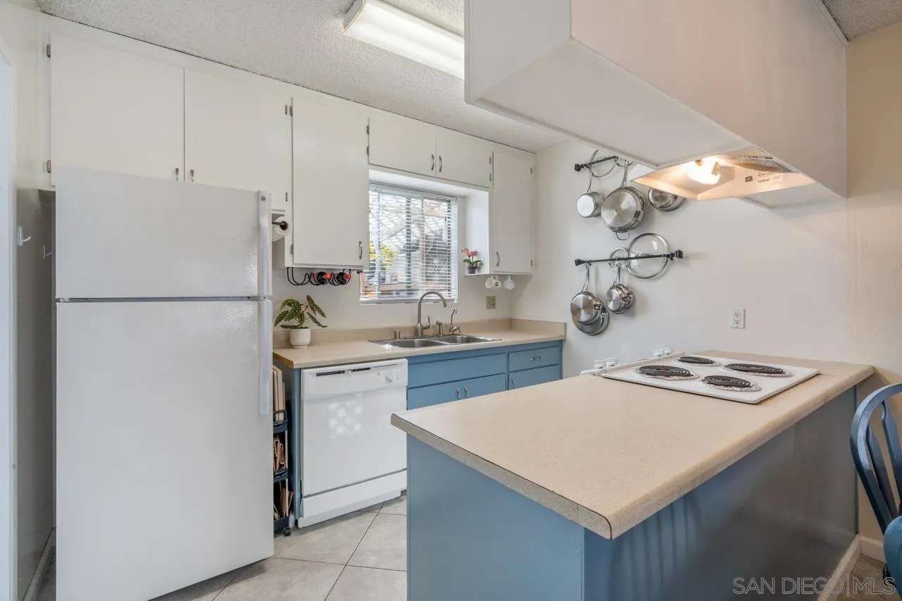 4530 Vandever Avenue, Unit 6 San Diego, CA 92120 - Photo 6 of 25 a kitchen with a sink a stove a refrigerator and white cabinets