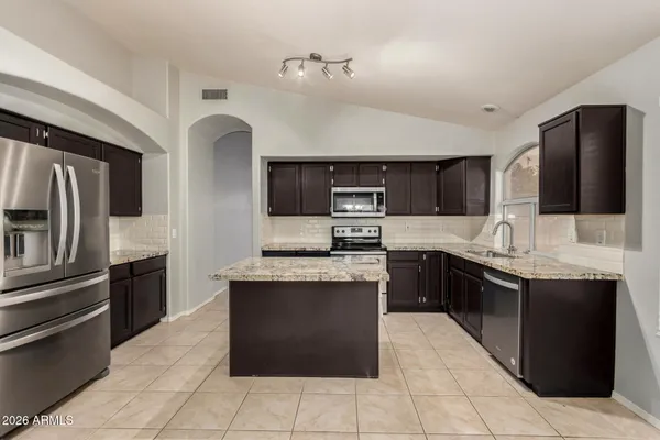 a kitchen with stainless steel appliances granite countertop a refrigerator and a stove top oven