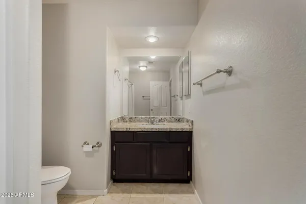 a bathroom with a granite countertop sink a toilet and a mirror