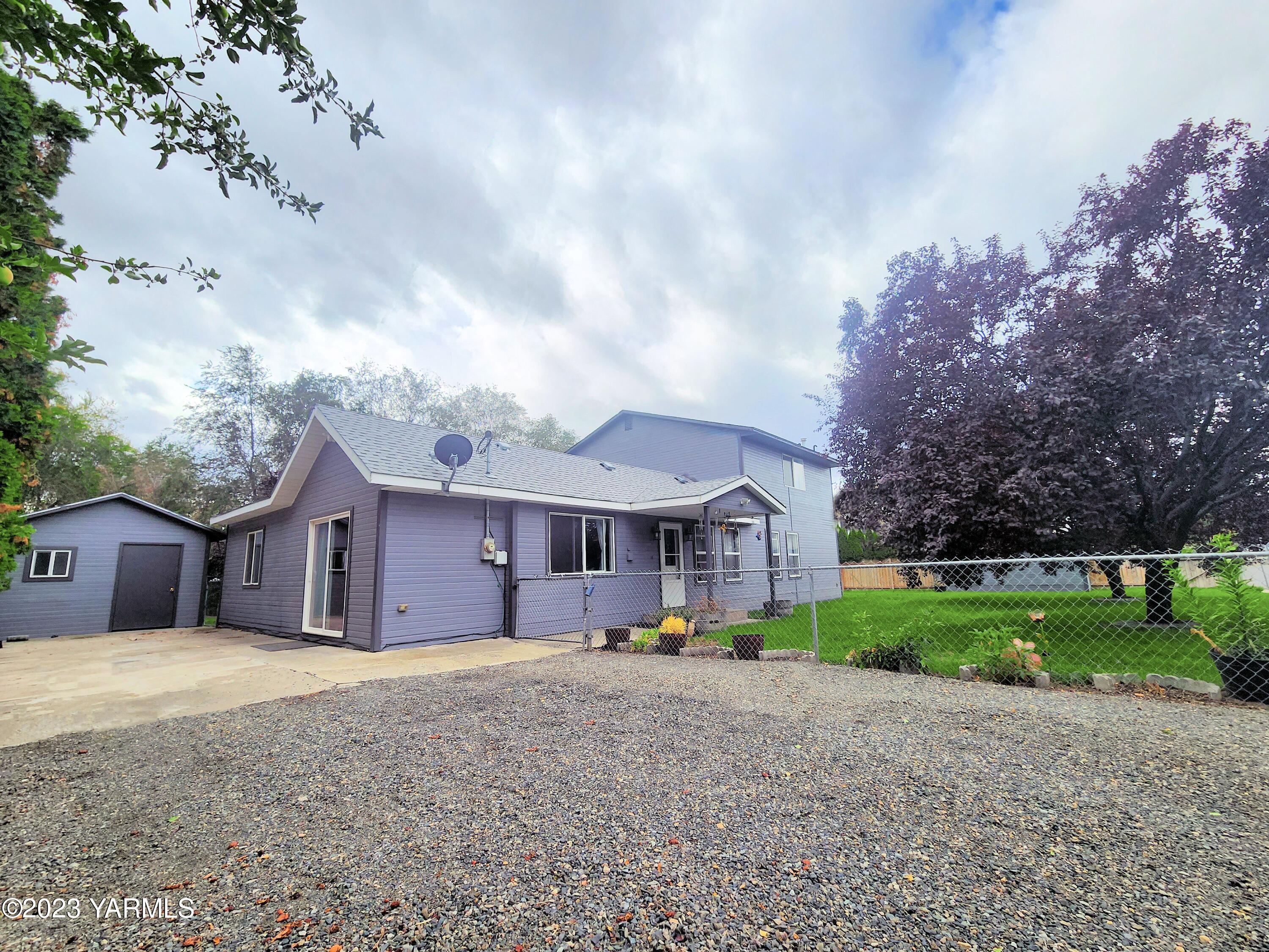 a view of a house with a yard and large trees