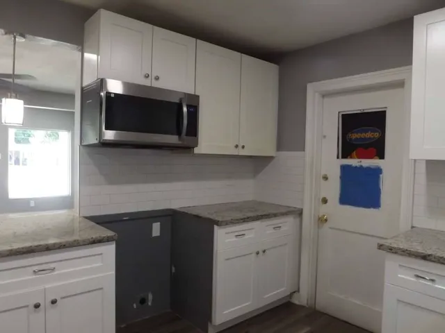 a kitchen with granite countertop white cabinets stainless steel appliances and a sink