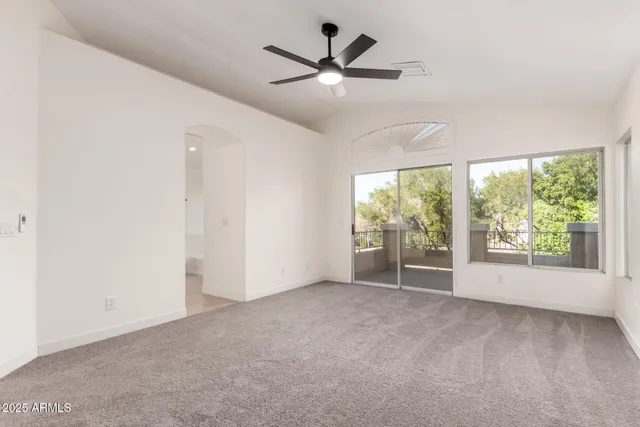 an empty room with windows and ceiling fan
