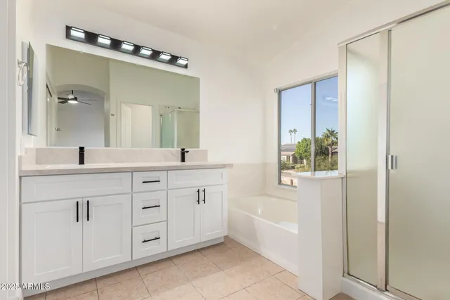 a bathroom with a double vanity sink mirror and bathtub