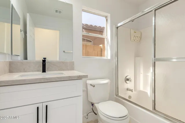 a bathroom with a granite countertop sink toilet a mirror a vanity and shower