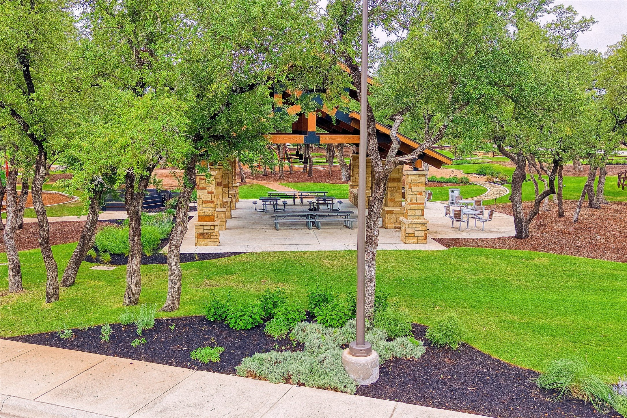 2408 Nate's Place Georgetown, TX 78633 - Photo 36 of 40 A community gathering spot with a stone and wood pavilion, nestled among vibrant trees and green lawns.