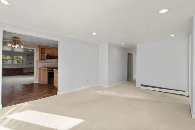 a view of an empty room with kitchen and a window