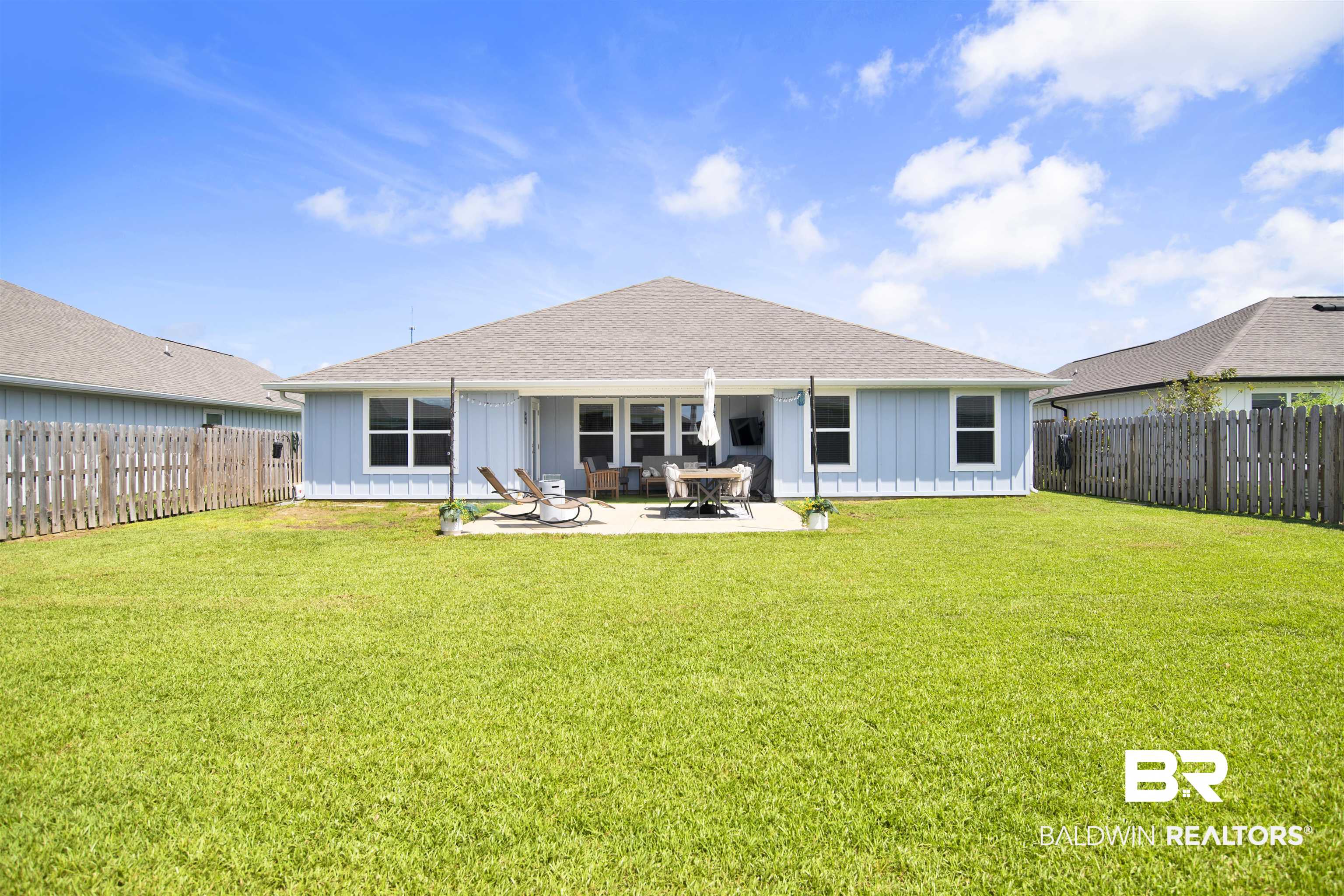 22301 Early Dawn Circle Foley, AL 36535 - Photo 36 of 45 Expansive grassy backyard featuring a concrete patio, light blue exterior siding, multiple windows, and a privacy fence