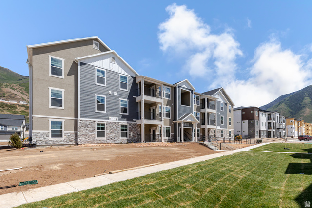 Multi-story residential buildings featuring varied siding materials including light-toned stucco, horizontal blue siding, white vertical siding, and a stone veneer base