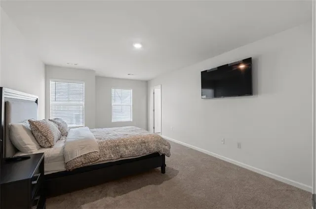 a bedroom with a bed a flat screen tv and guitar
