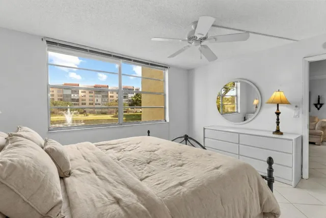 a bedroom with a bed mirror on table and window
