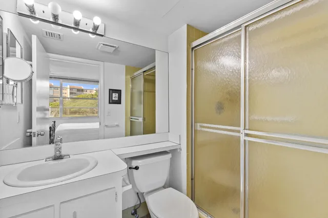 a bathroom with a toilet sink vanity and shower