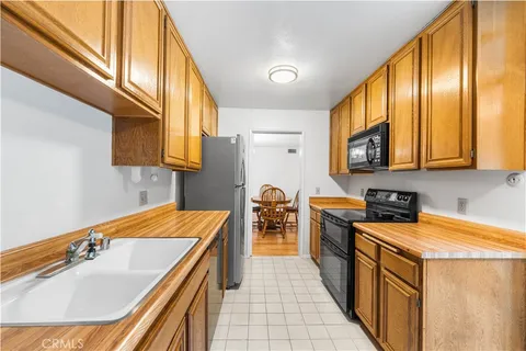 a kitchen with stainless steel appliances granite countertop a sink a stove top oven a chimney cabinets and a refrigerator