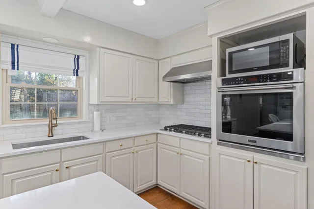 a kitchen with white cabinets and stainless steel appliances