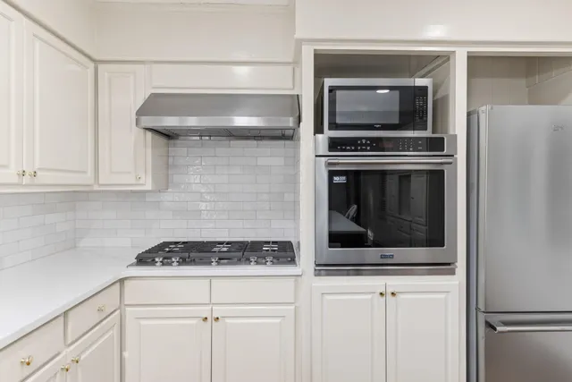 a kitchen with granite countertop white cabinets and stainless steel appliances