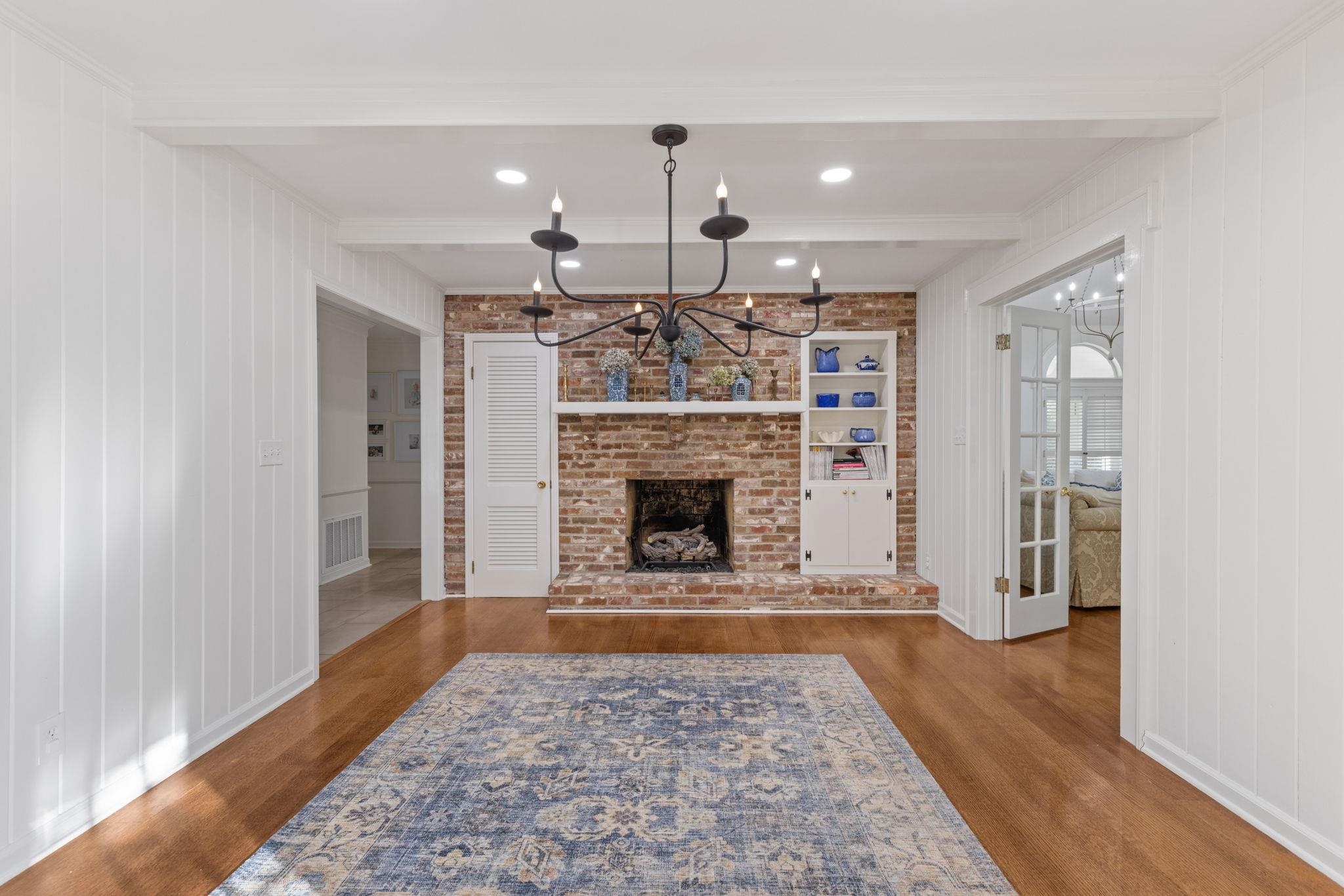 1201 West Clover Lane Corinth, MS 38834 - Photo 2 of 35 Unfurnished living room with a chandelier, a brick fireplace, wood finished floors, beamed ceiling, and wood walls