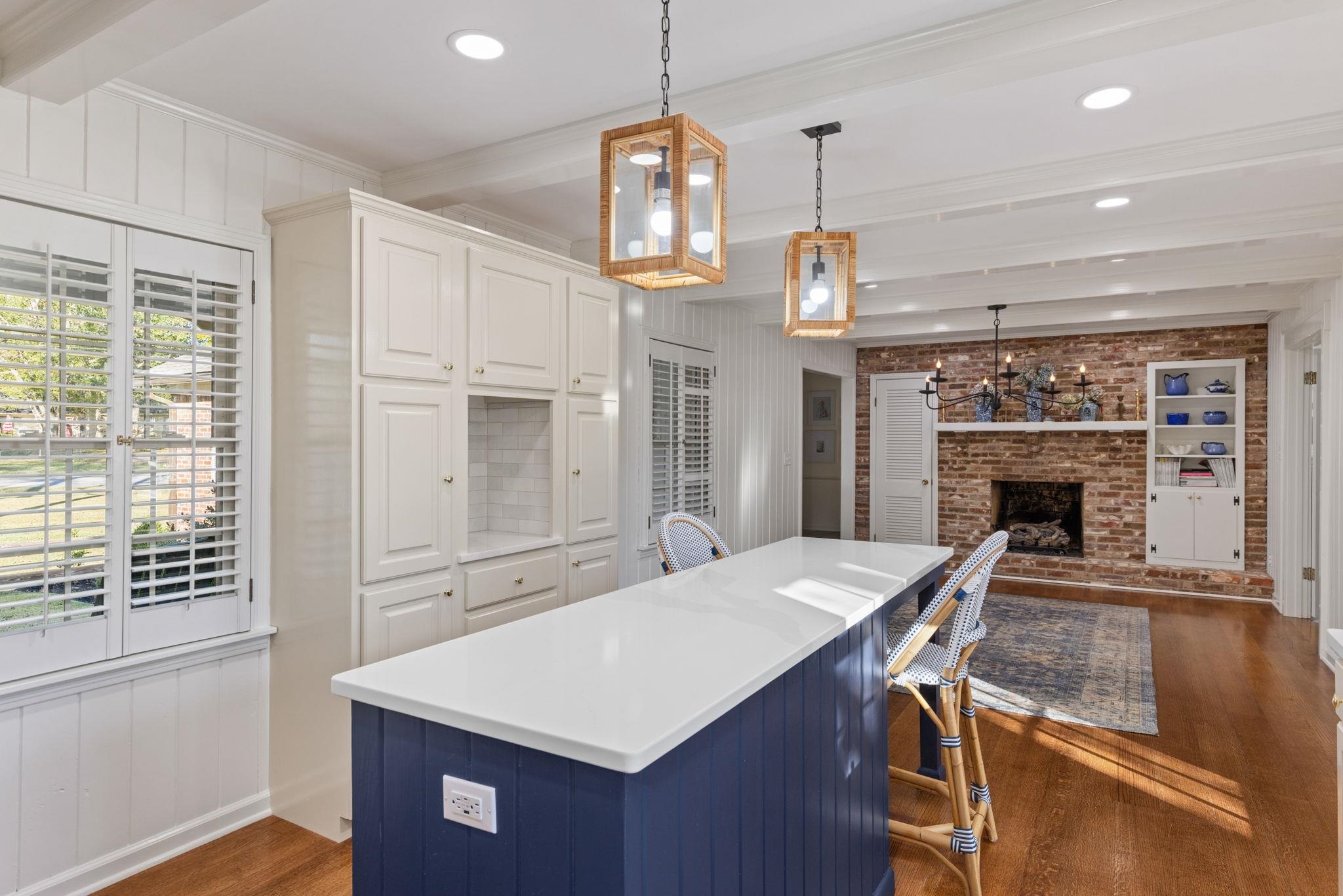 1201 West Clover Lane Corinth, MS 38834 - Photo 23 of 35 Kitchen with beamed ceiling, hanging light fixtures, dark wood-type flooring, white cabinetry, and a brick fireplace