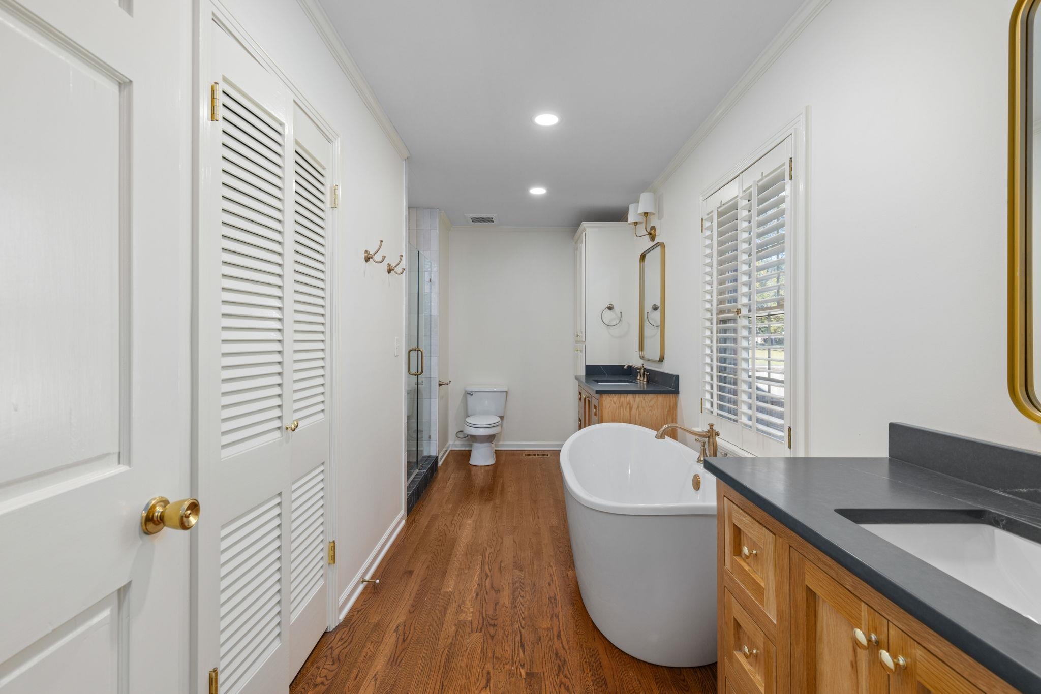 1201 West Clover Lane Corinth, MS 38834 - Photo 4 of 35 Full bathroom with two vanities, dark wood finished floors, a soaking tub, a shower stall, and crown molding