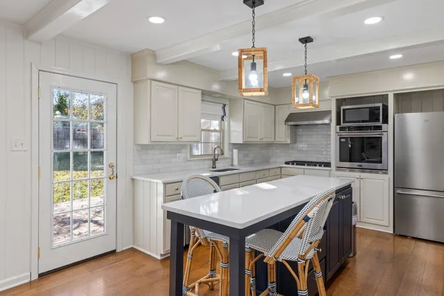 a kitchen with granite countertop a table chairs stainless steel appliances and wooden floor