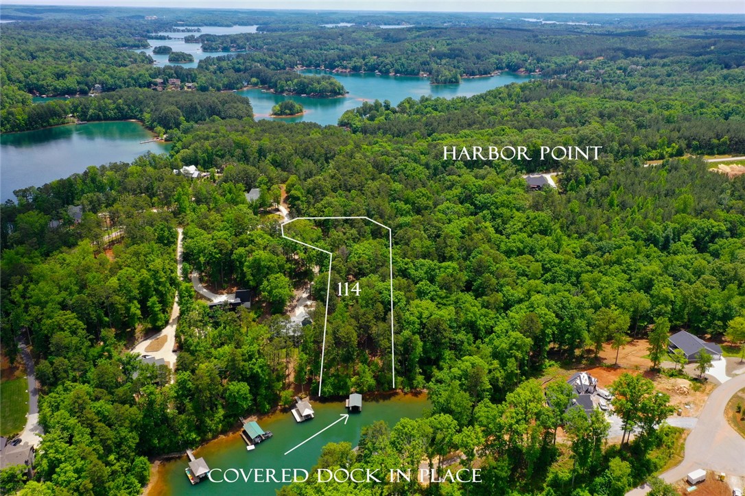 This aerial view showcases a lush, tree-lined lot with tranquil waterfront access and private boat docks.