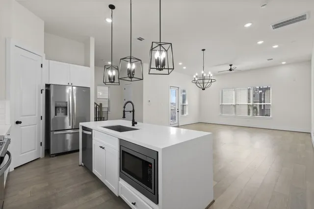 a kitchen with stainless steel appliances granite countertop a sink a stove a refrigerator and island with wooden floor