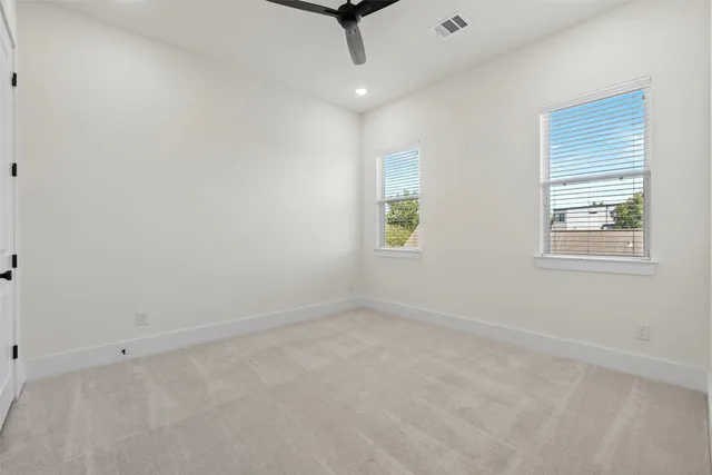 an empty room with windows and ceiling fan