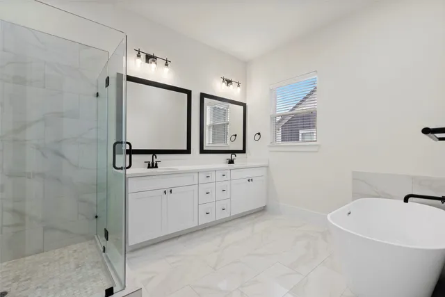 a spacious bathroom with a double vanity sink mirror and bathtub